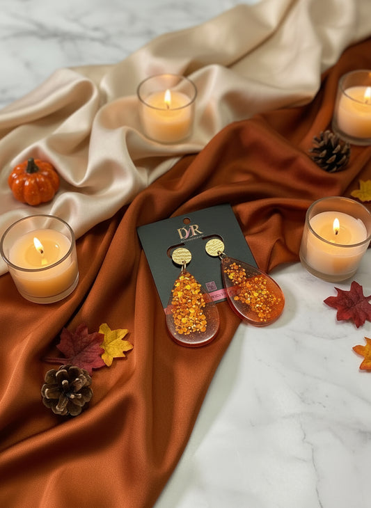 Orange earrings with glitter on a black card with 'DBR' branding