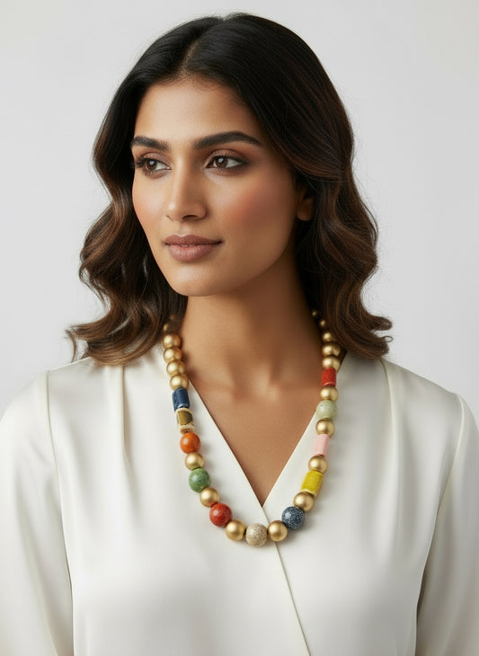 Colorful beaded necklace on a black mannequin with a plant in the corner