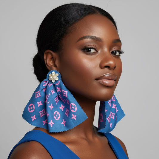 Blue earrings with pink patterns on a marble surface