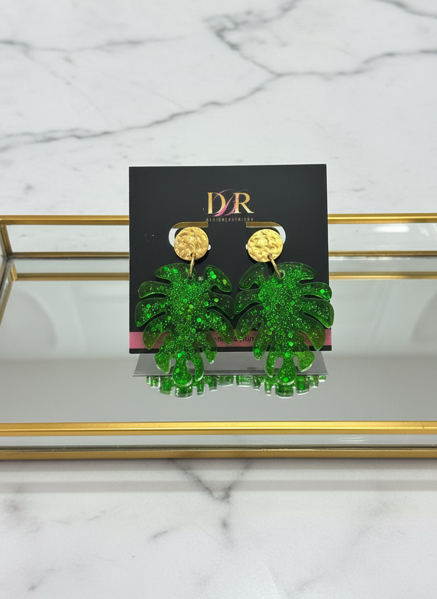 Green glittery leaf-shaped earrings on a black card with 'DBR' branding.