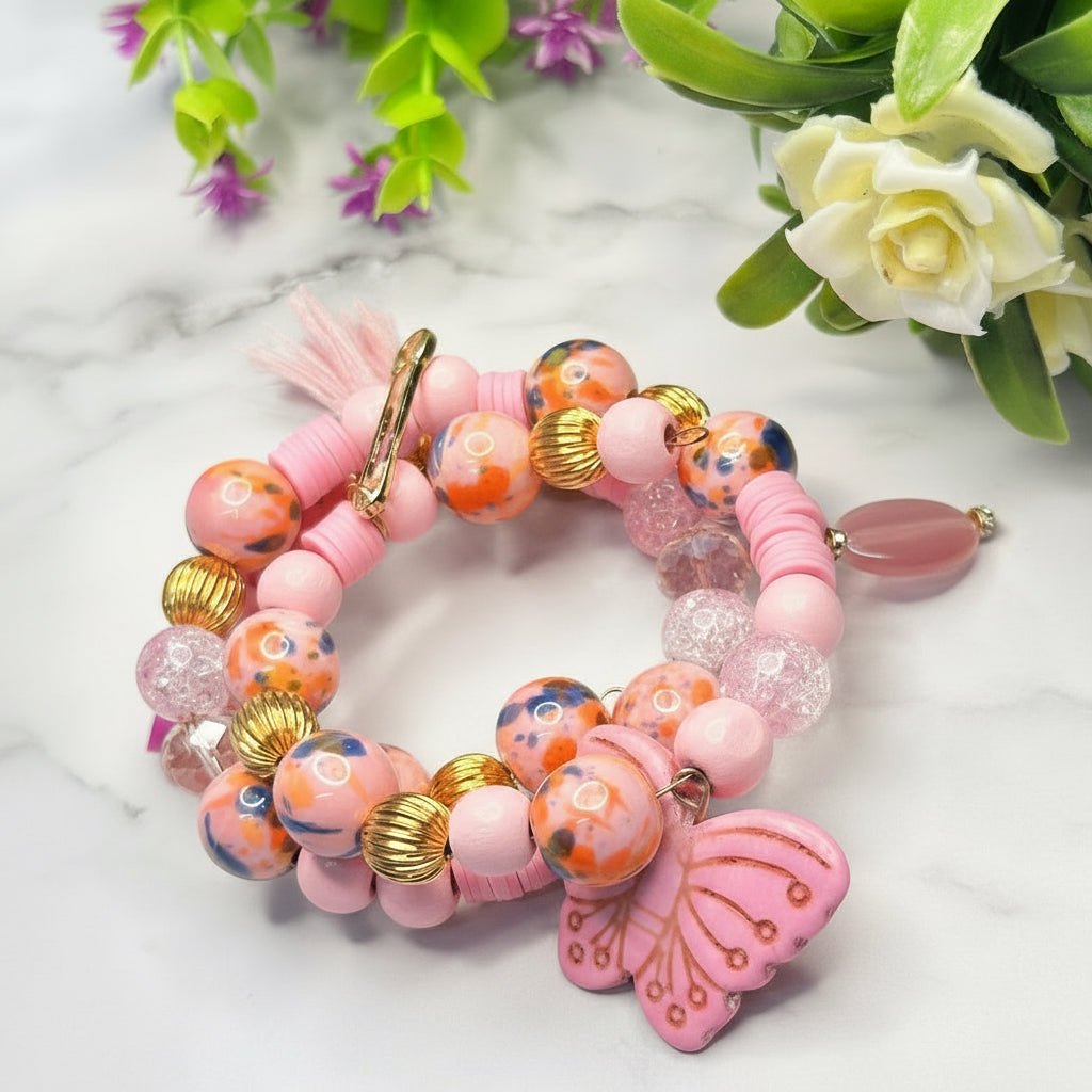 Colorful beaded bracelet with a butterfly charm on a marble surface with flowers.