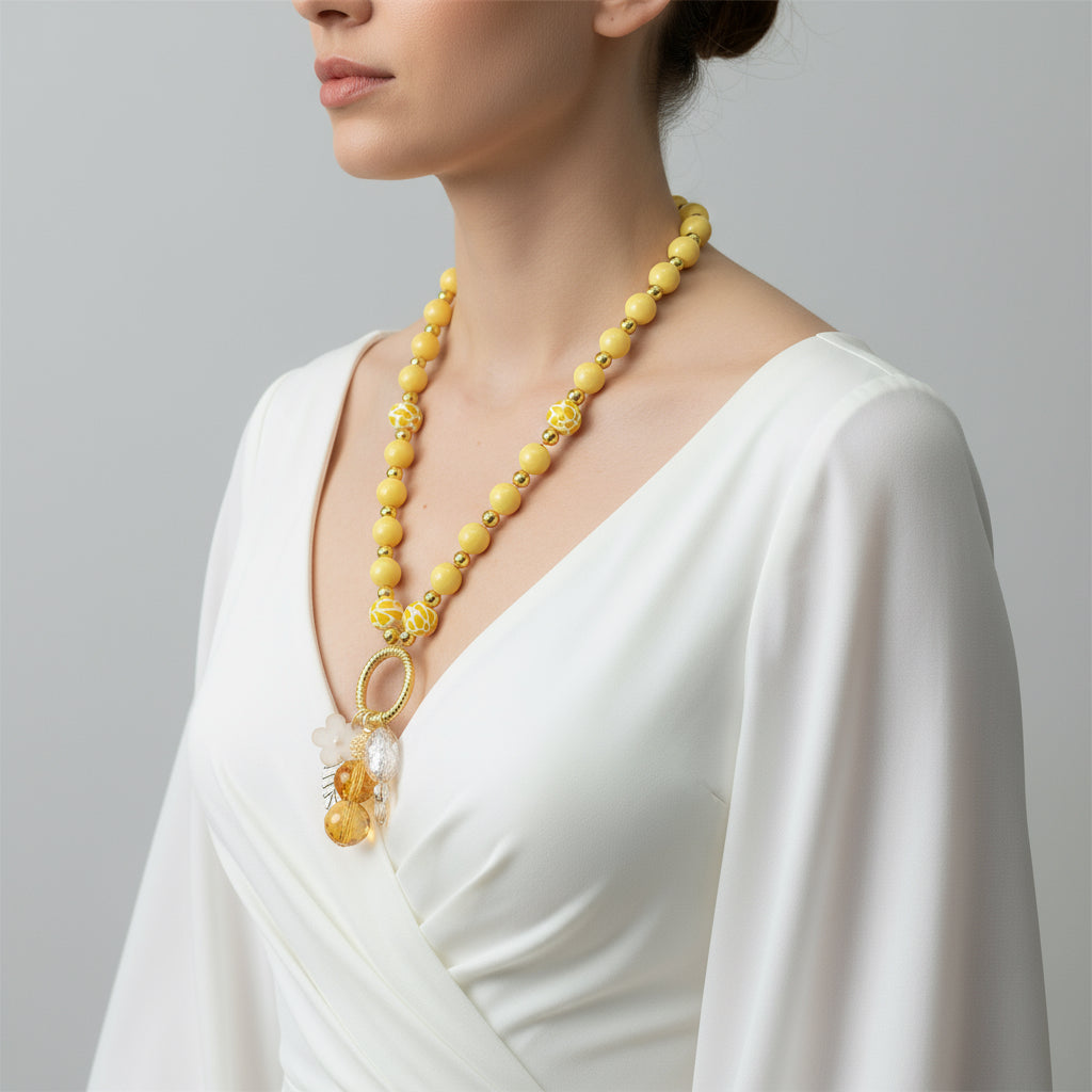 Yellow beaded necklace with floral and circular pendants on a model.