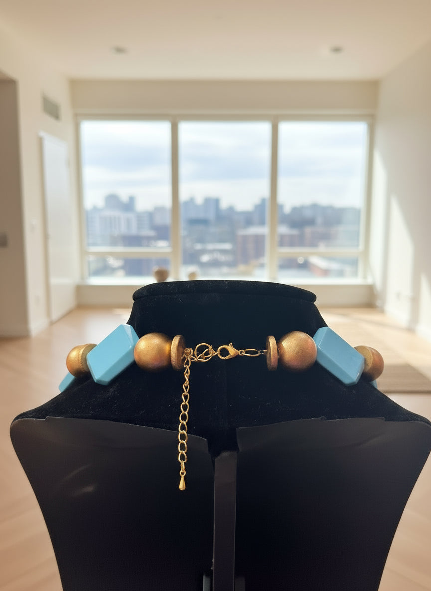 Necklace with gold beads and blue accents on a black background