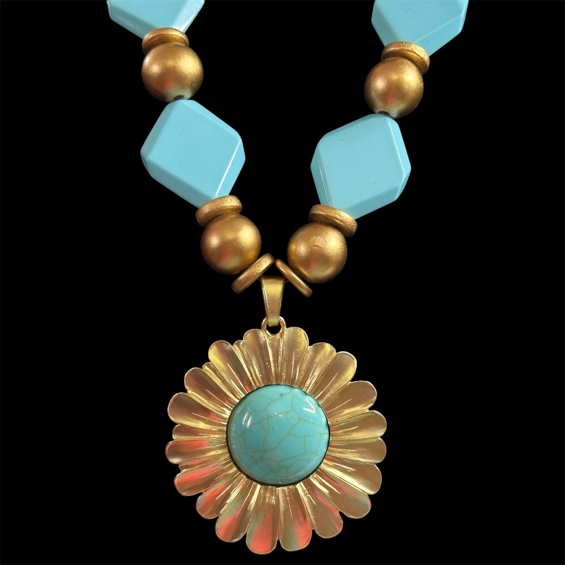 Necklace with turquoise beads and a gold pendant on a black background